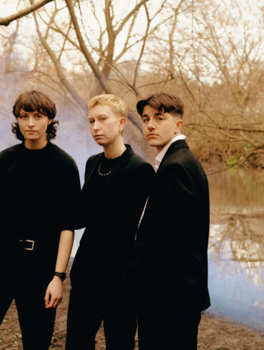 The three members of the band headboy standing beside a river