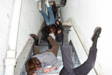 The members of the band Geese, falling down the stairs