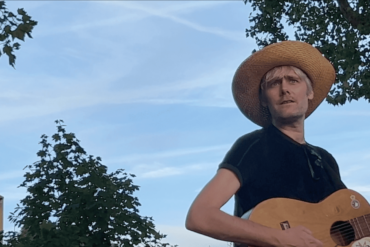 Alex Sebley from Pregoblin wearing a straw hat and holding a guitar.